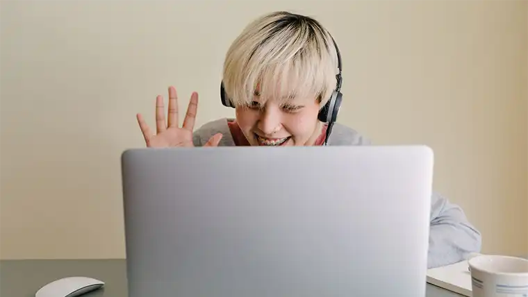 person smiling and waving in virtual meeting