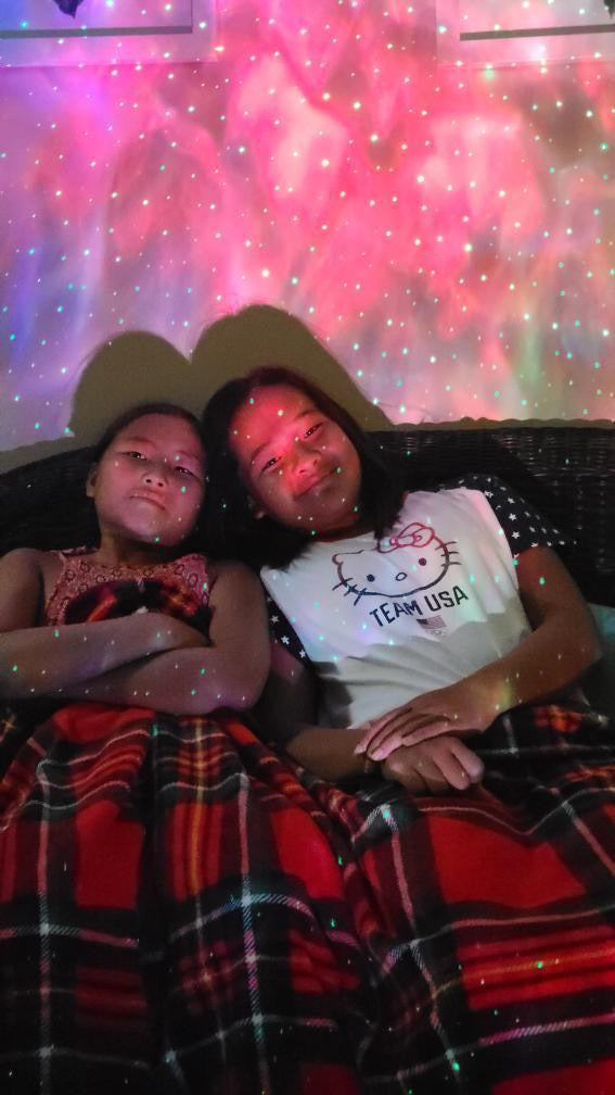 two smiling girls under a blanket with sky lite 2.0 behind them