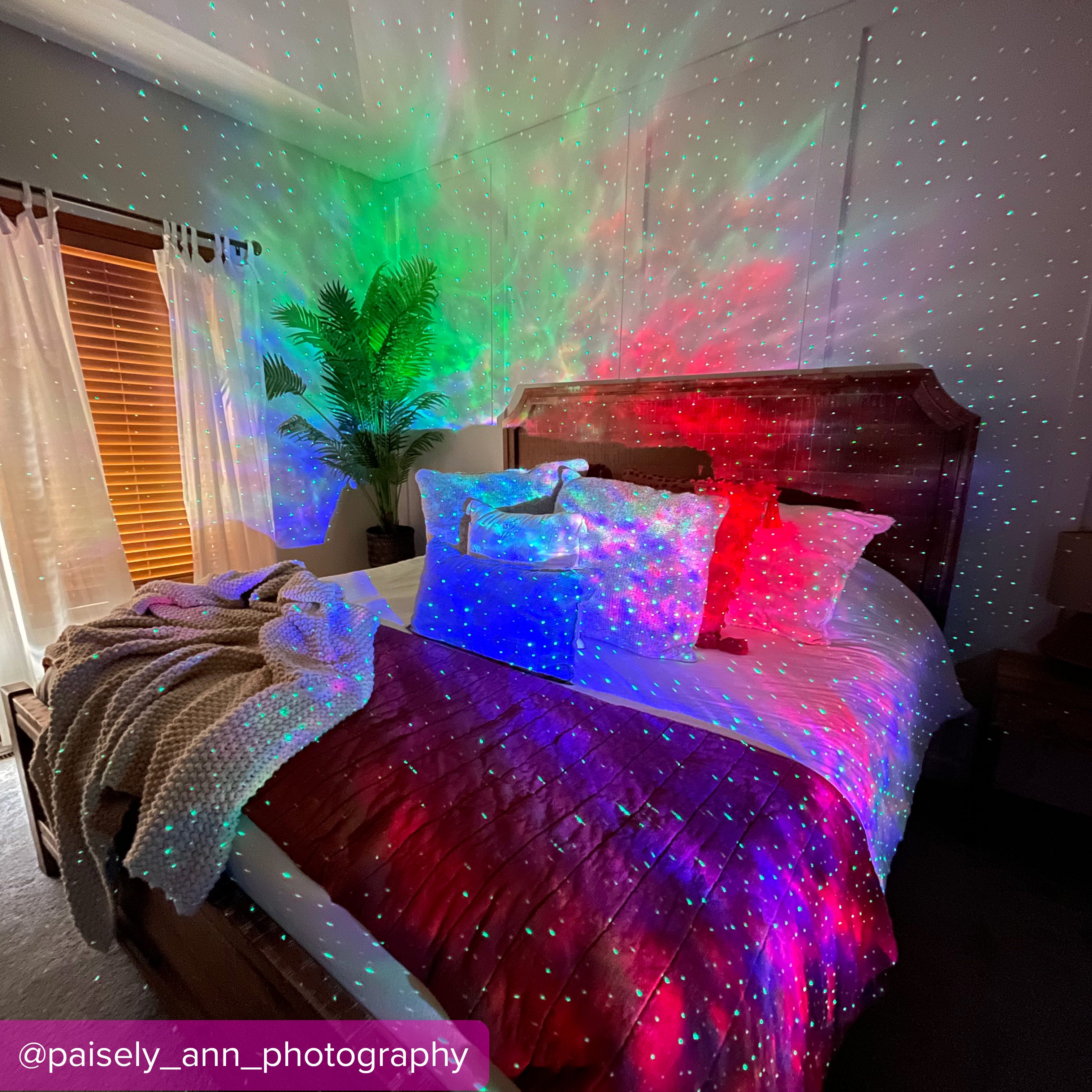 bed with pillows and wood headboard lit by colorful galaxy light