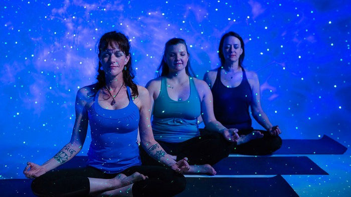 three women on yoga mats meditating