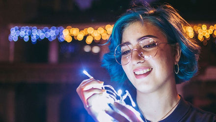 smiling woman holding string lights