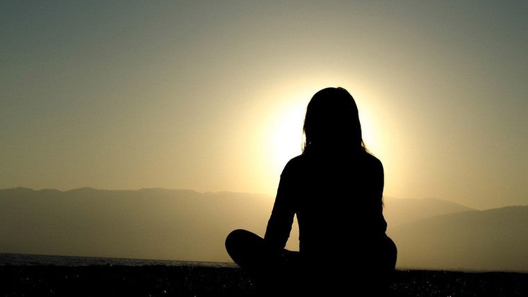 silhouette of a woman sitting in front of sunset
