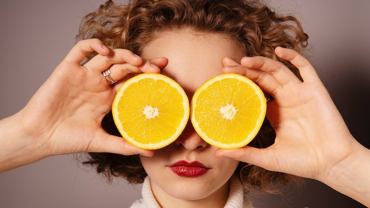 woman holding oranges in front of her eyes