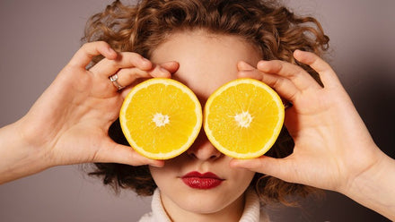 woman holding oranges in front of her eyes