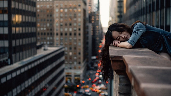 woman sleeping on ledge in city
