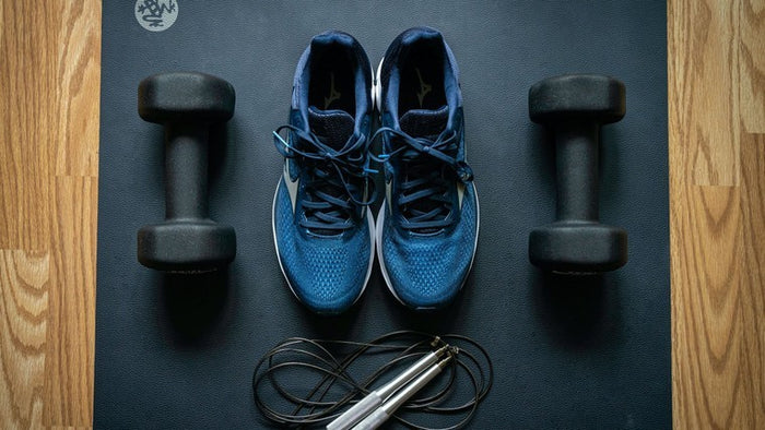 workout shoes and dumbells on yoga mat