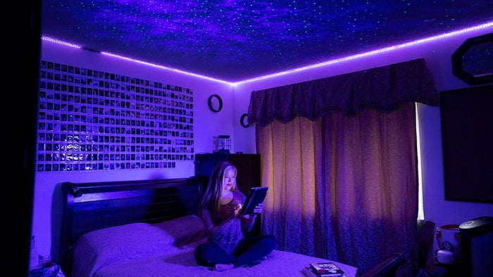 woman sitting on bed under galaxy lights