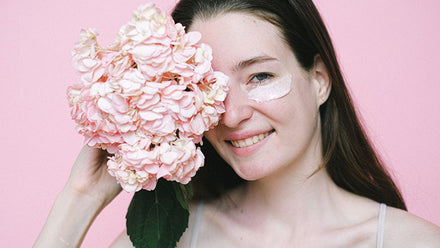 smiling woman with under eye masks holding flower