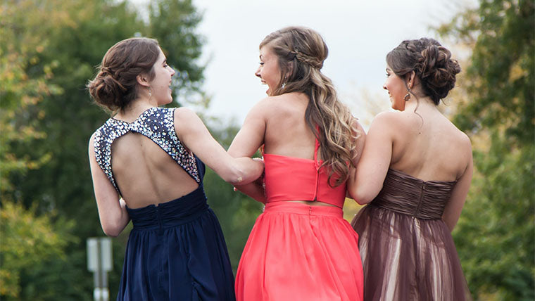 three smiling girls in prom dresses