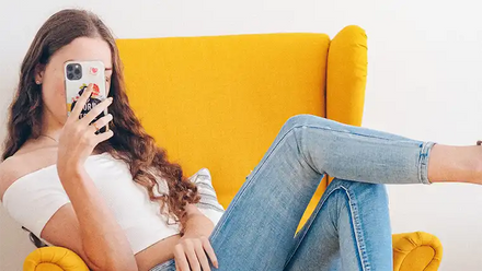 woman posing with phone on yellow chair