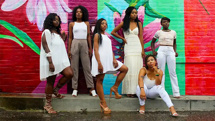 six woman posing in front of colorful wall