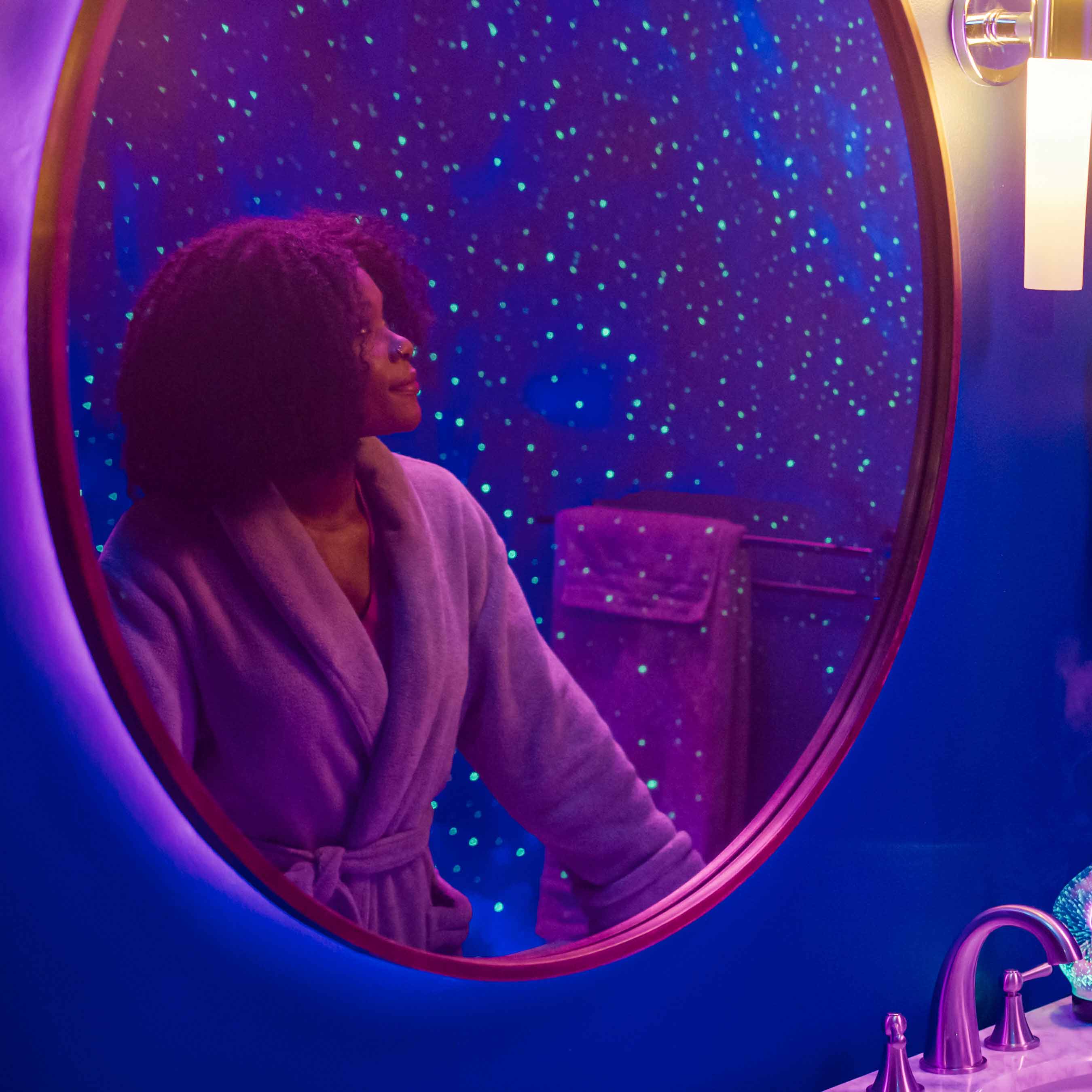 woman in bathroom looking at galaxy lights in mirror