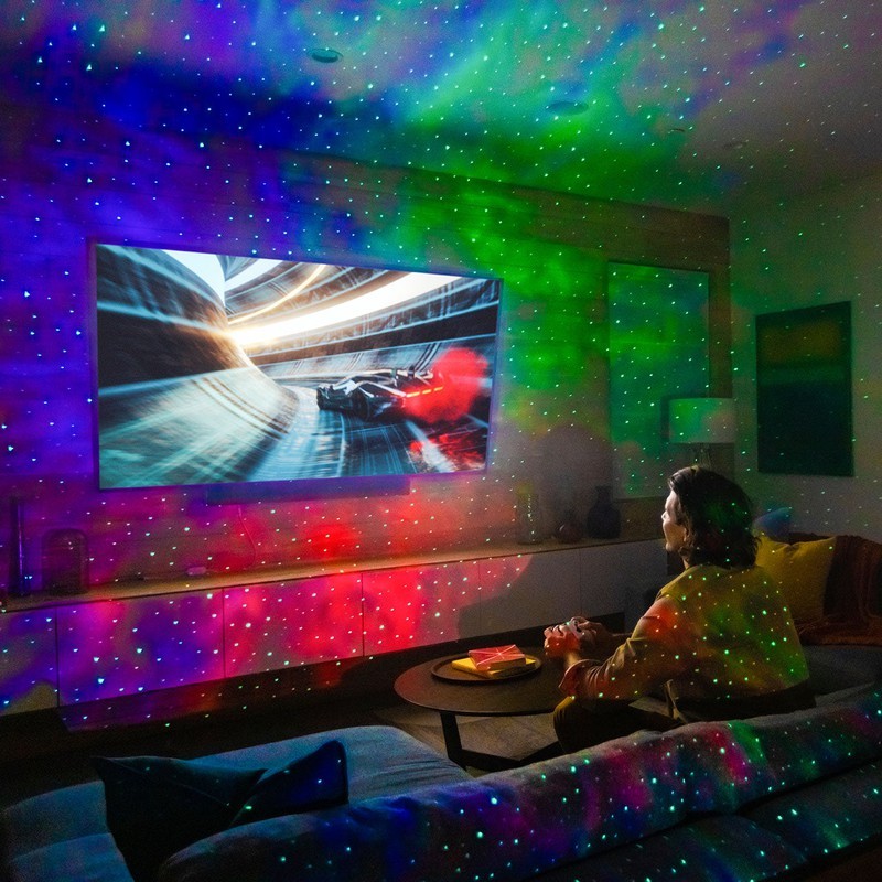 man playing video games with sky lite 2.0 multicolor galaxy projector in living room